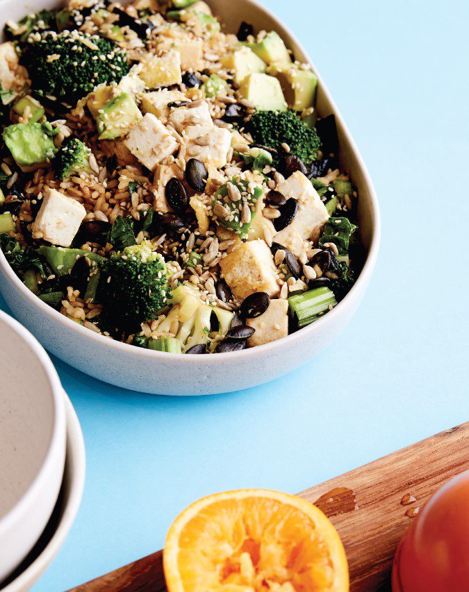 Large deep platter filled with a colourful mix of bright broccoli florets, tofu and sprinkled with seeds.